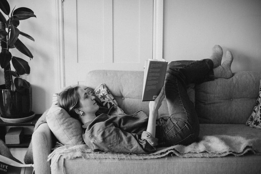 Business coach and copywriting reclines on the sofa reading 